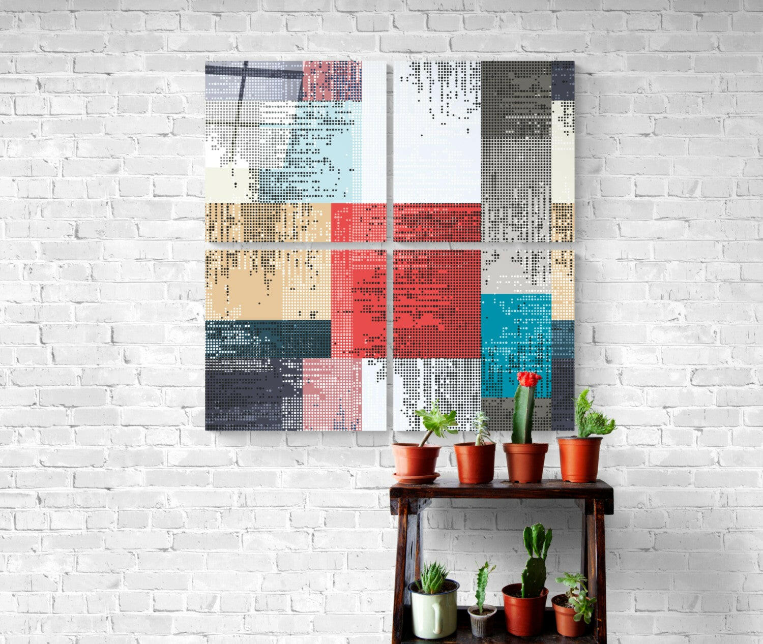 Dots Quadro glass wall art in red, blue, tan, and gray displayed above wooden shelf holding potted cacti against white brick wall.