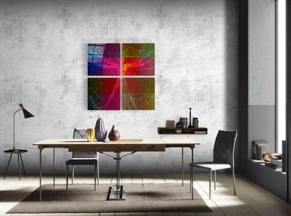 Four-panel colorful glass wall art with vibrant magenta, blue, green, and gold tones displayed above a wooden desk in a modern office setting.