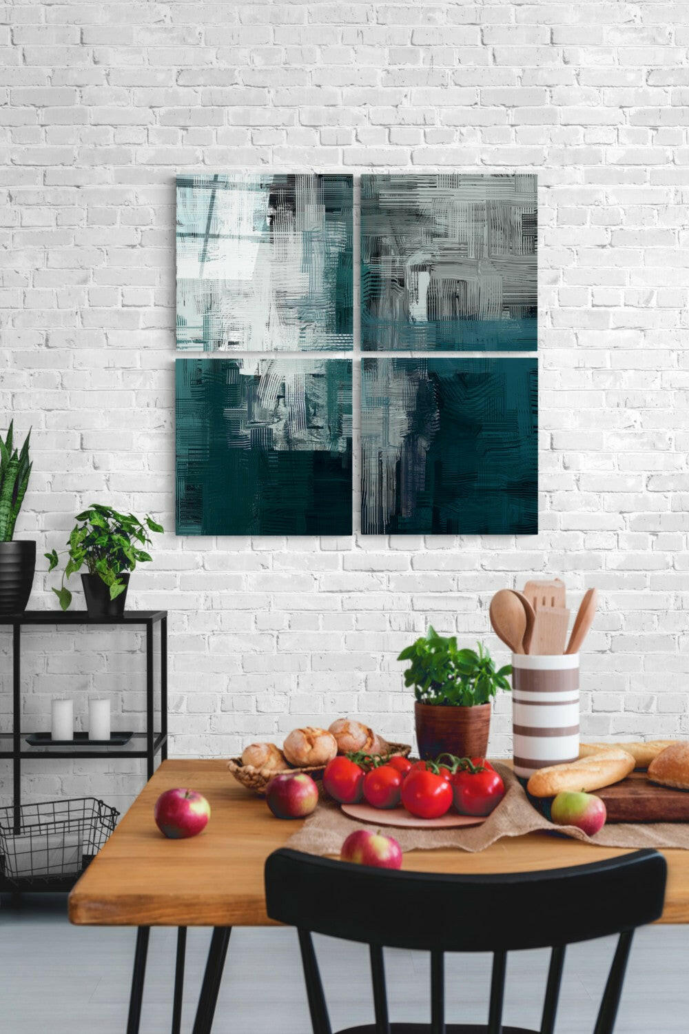 Four-panel teal and white abstract glass art displayed on white brick wall above wooden table with fresh produce and kitchen items.