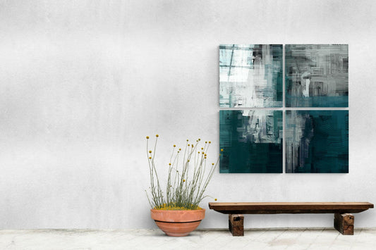 Four-panel green and white glass wall art displayed above wooden bench with potted yellow flowers against white wall.