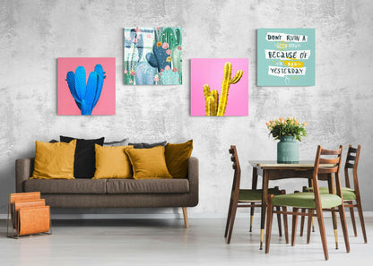 Four cactus-themed glass wall art pieces displayed above a gray sofa with yellow pillows in a modern living room setting.