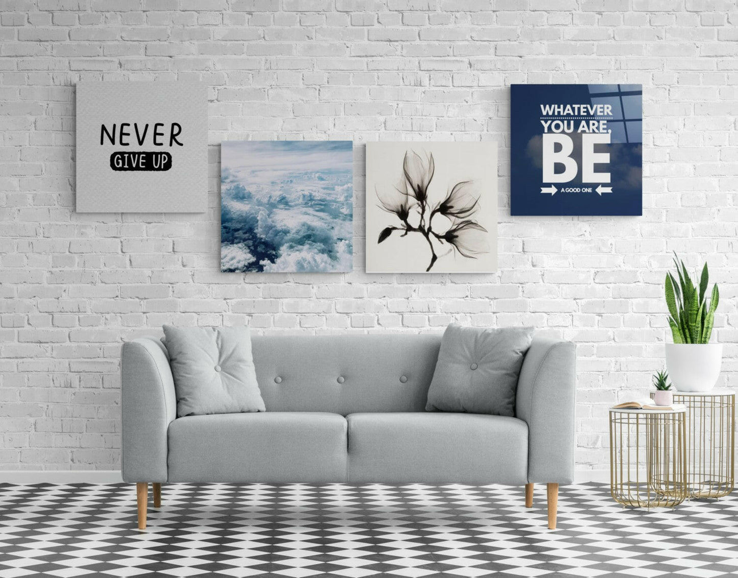 Four motivational glass wall art prints displayed above a gray sofa on a white brick wall, featuring text and nature imagery in blue, white, and black.