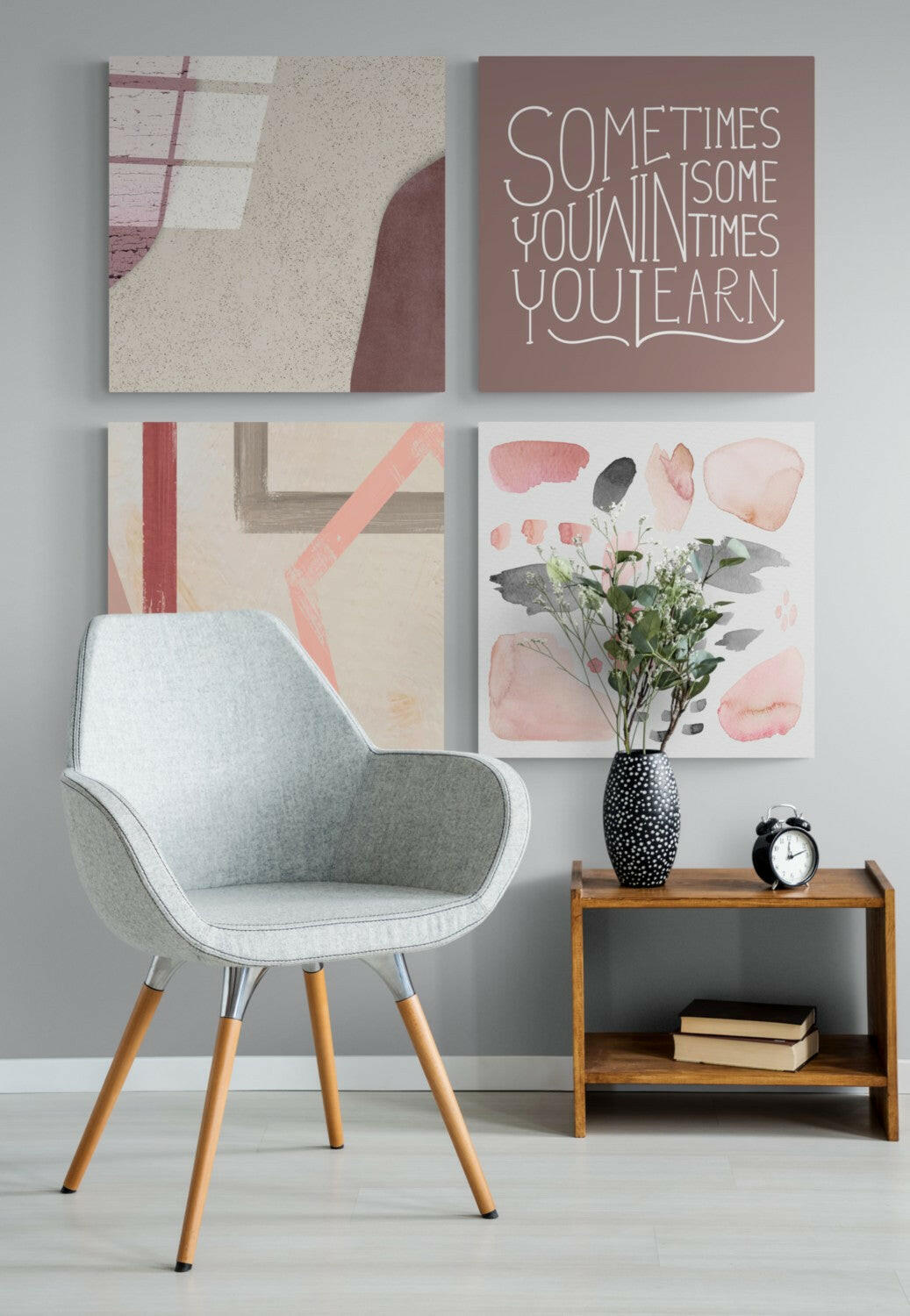 Modern interior scene with light gray mid-century chair beside wooden side table displaying black clock and vase with pink flowers, four framed wall artworks above including motivational text on mauve background.