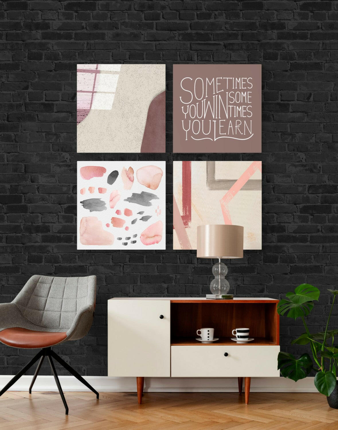 Four-panel glass wall art set in muted pink and gray tones displayed above mid-century furniture against black brick.