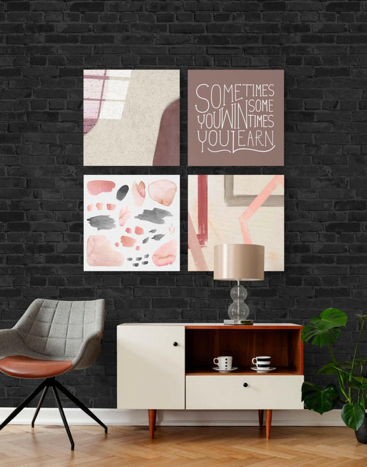 Four-panel glass wall art set in muted pink and gray tones displayed above mid-century furniture against black brick.