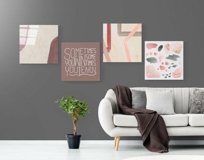 Mauve glass wall art with white outlined text reading "Sometimes you win sometimes you learn" displayed above a white sofa in a styled living room interior.