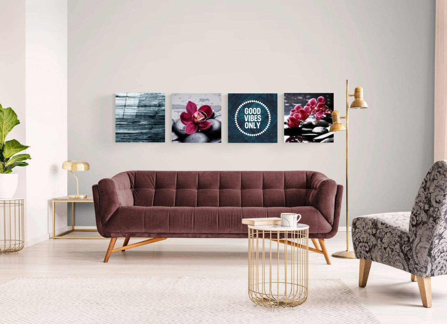 Four glass wall art panels above burgundy sofa displaying blue wood texture, red orchid on stones, "Good Vibes Only" text, and pink orchids with spa stones.