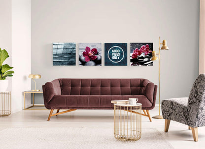 Four glass wall art panels above burgundy sofa displaying blue wood texture, red orchid on stones, "Good Vibes Only" text, and pink orchids with spa stones.