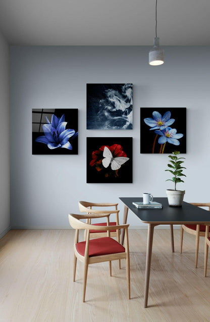 Modern dining room interior featuring four glass wall art panels displaying blue flowers, red and white butterfly, and dark cloudy imagery above wooden table and chairs.