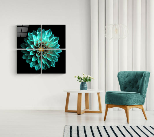 Four-panel glass wall art displaying a turquoise dahlia flower on black background, hung above a white side table with teal chair.