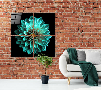 Four-panel glass wall art displaying a turquoise dahlia flower on black background, installed above white sofa with green throw blanket in brick loft interior.