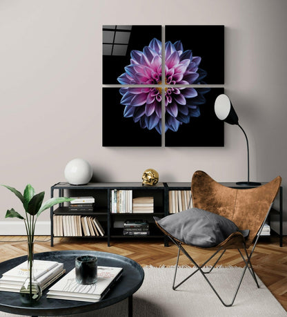 Four-panel glass wall art displaying a purple and pink dahlia flower centered on black background, hung above a black shelving unit in a modern living room.