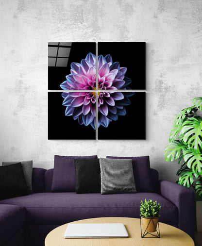Four-panel glass wall art displaying a purple and pink dahlia flower with yellow center on black background, installed above a purple sofa.
