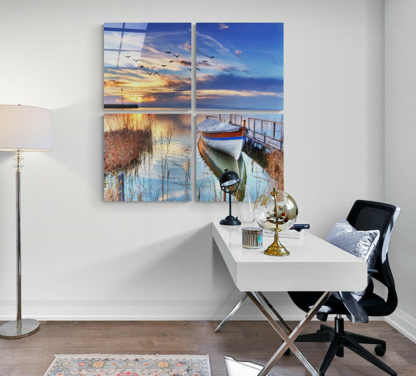 Four-panel glass wall art displaying coastal and sunset scenes including flying birds, reeds, and moored boats above a white desk.
