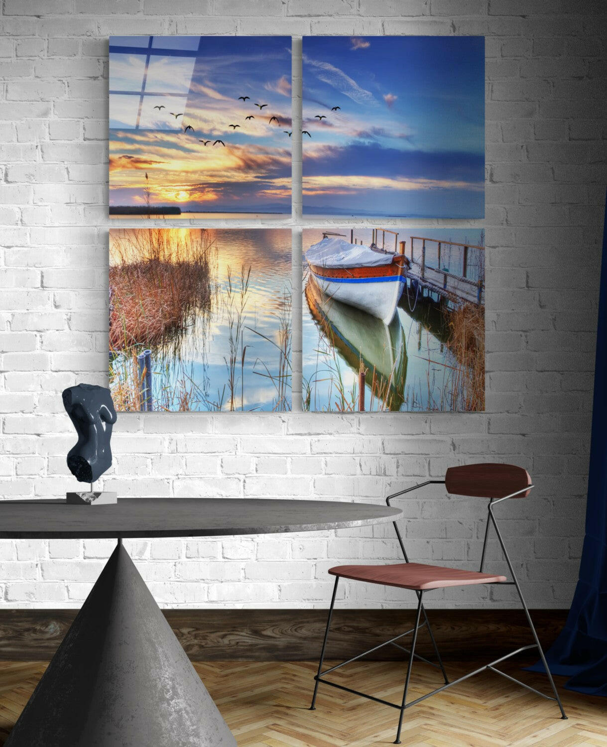 Four-panel glass wall art displaying serene waterside scenes: sunset sky with flying birds, calm water reflections, reeds, and moored boat.