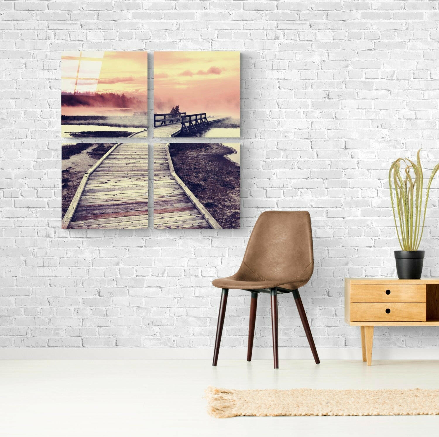 Four-panel glass wall art depicting a wooden boardwalk extending toward a sunset over water with warm golden and pink tones.