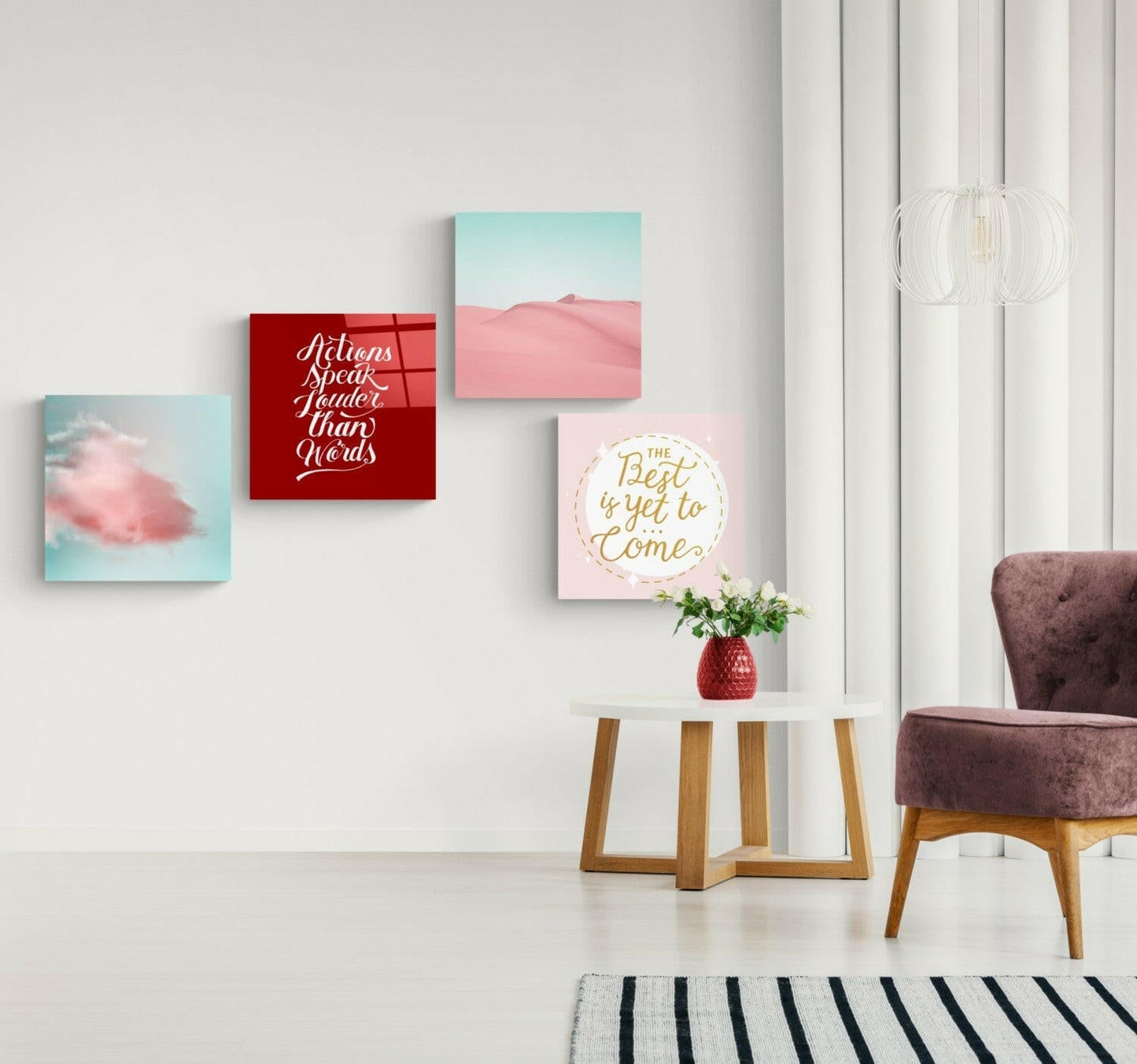 Modern living room interior with four motivational wall art prints in pink, red, and turquoise tones displayed above a round side table.