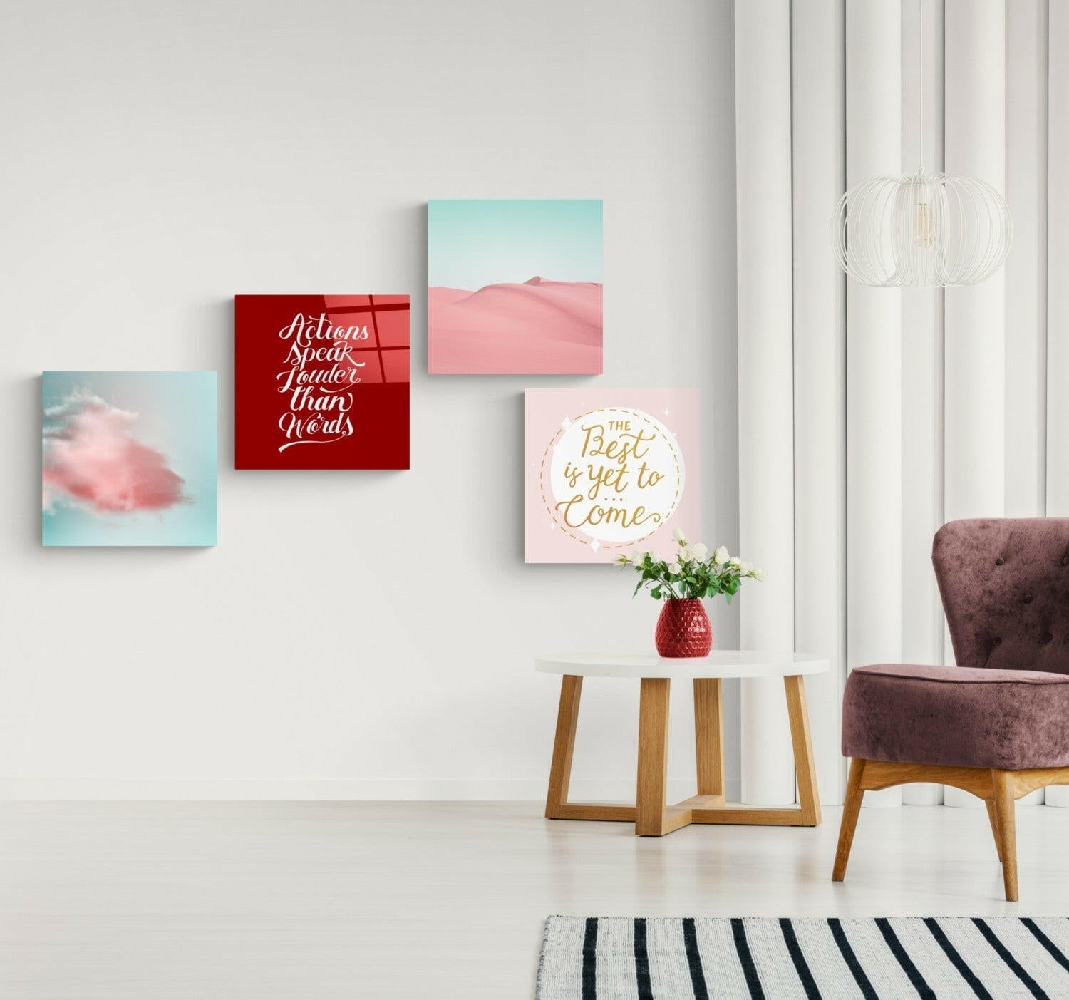 Modern living room interior with four motivational wall art prints in pink, red, and turquoise tones displayed above a round side table.
