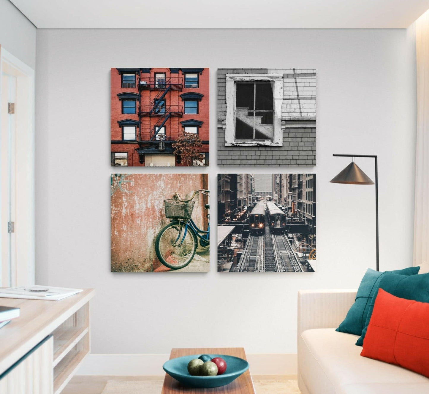 Four framed glass wall art prints displayed in a 2x2 grid showing urban architecture, a bicycle, and train tracks in a modern living room setting.