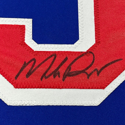 Close-up of autographed red chest stripe on blue New York Rangers hockey jersey showing handwritten signature.