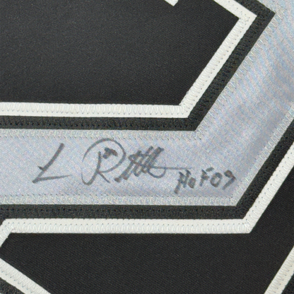 Close-up of autographed signature on gray fabric strip bordered by black and white stripes on hockey jersey.
