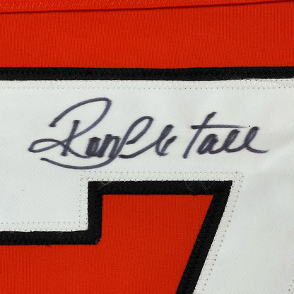 Close-up of handwritten signature "Ron Hextall" in blue ink on white jersey label with red and black fabric visible.