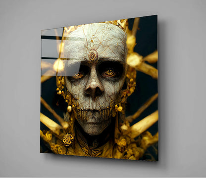 Angled view of glass wall art depicting a pale skull with golden eyes and ornate gold jewelry against dark background.