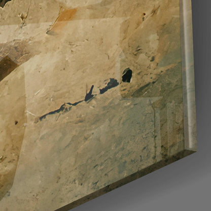 Angled view of glass wall art with sandy beige surface and dark shadows cast by two silhouetted figures on textured terrain.
