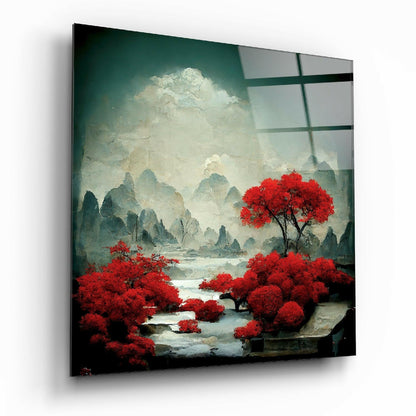 Square glass wall art panel displaying misty mountains with vibrant red trees reflected in water, viewed at angle showing black frame edges.