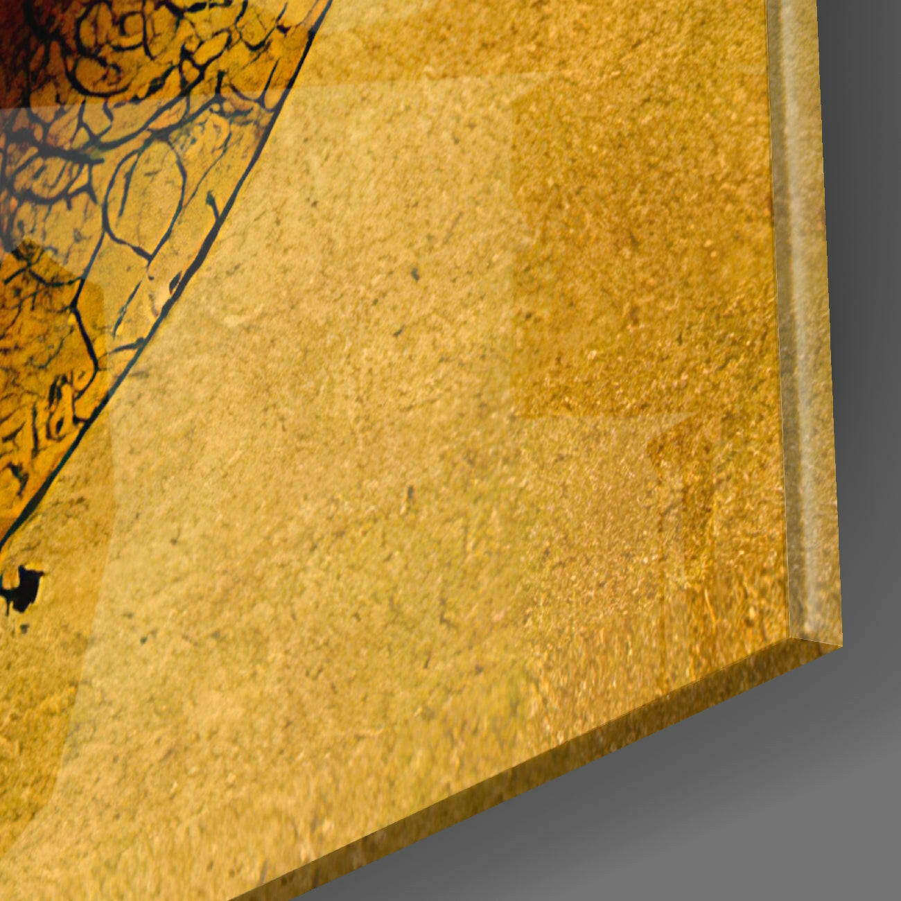 Close-up angled view of gold textured glass surface with decorative black calligraphy visible at upper left edge.