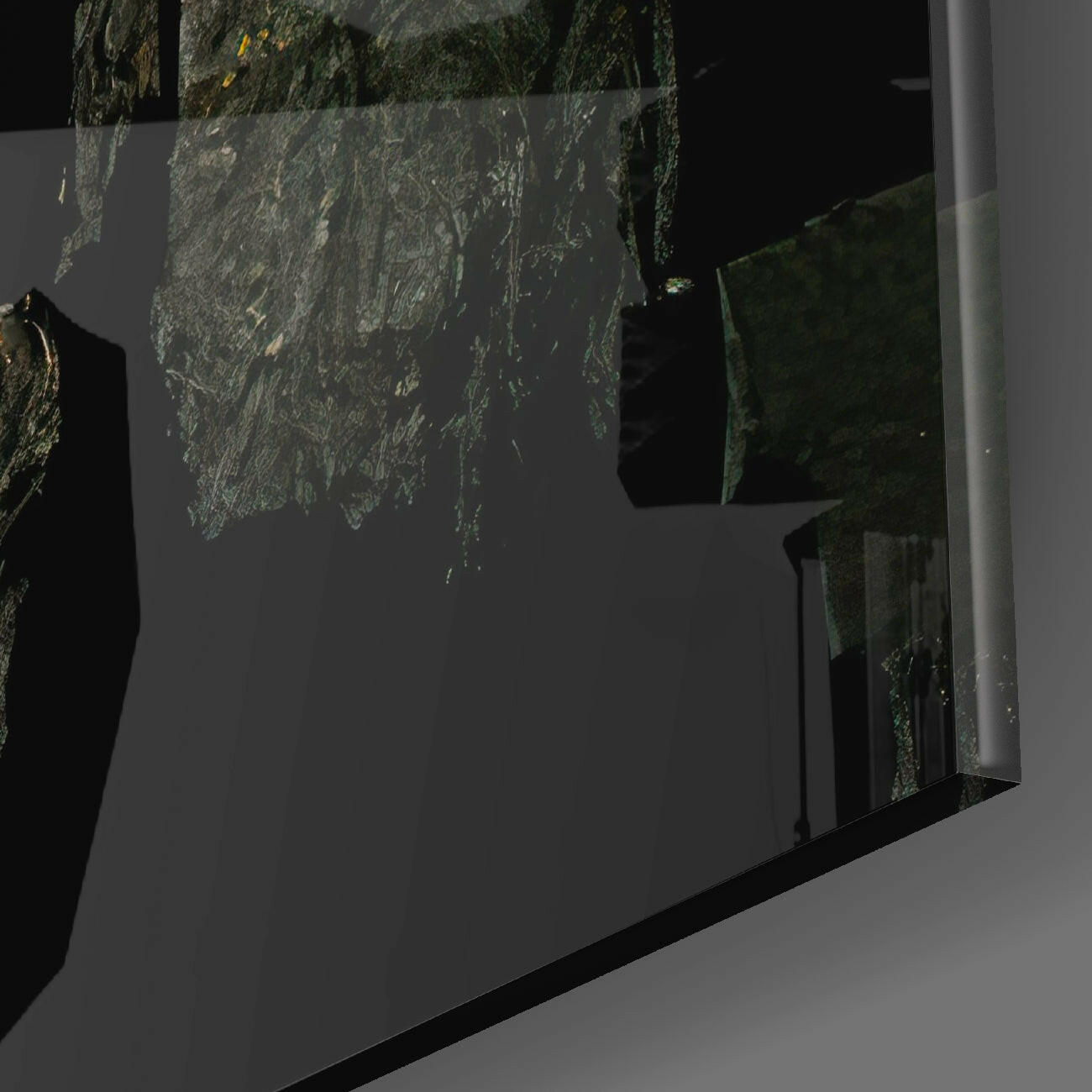 Lava Glass Wall Art mounted on gray wall, showing textured green and gold glass surface with black frame edge in angled view.