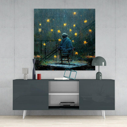 Glass wall art depicting a figure in blue jacket sitting on chair under falling golden stars in dark teal stormy setting, displayed above gray media console.