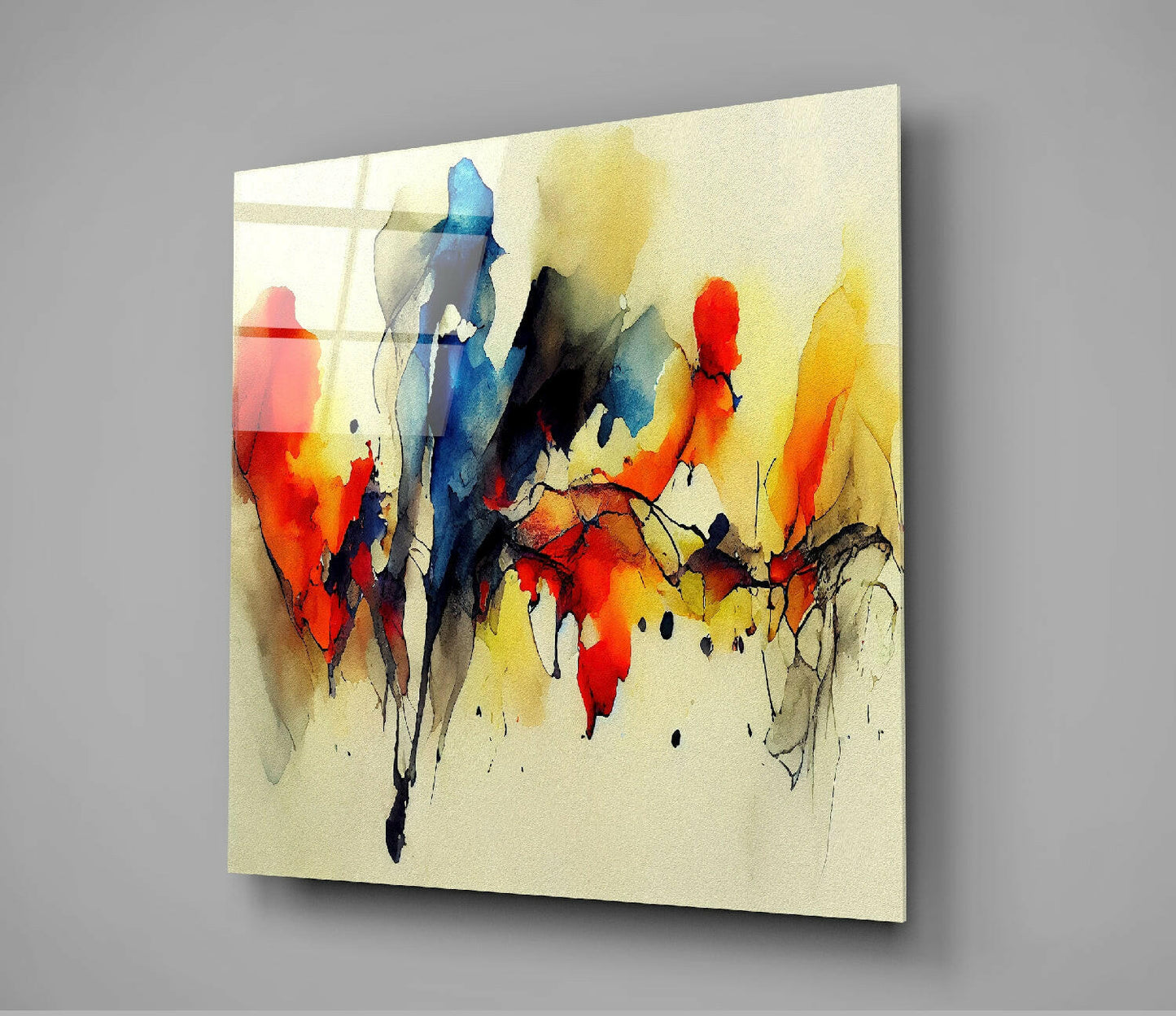 Abstract glass wall art panel displaying vibrant watercolor-style figures in red, blue, yellow, and black on cream background, mounted at angle against gray wall.