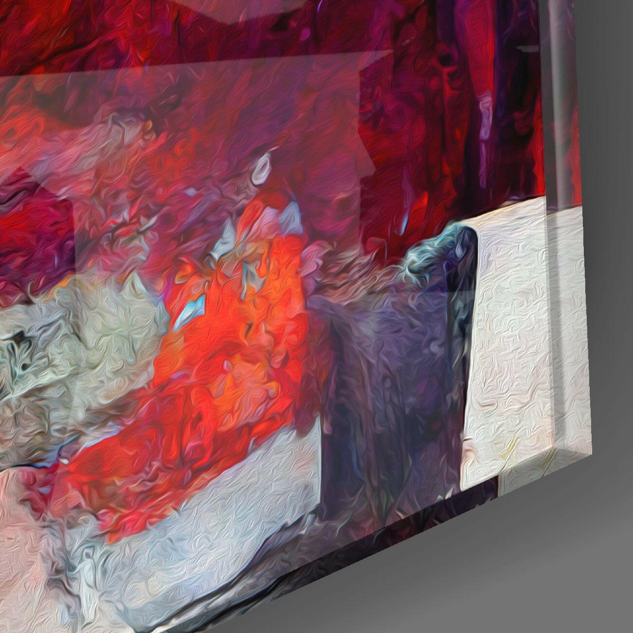 Angled view of glass wall art displaying vibrant red and purple swirling patterns with white textured surface visible on right edge.