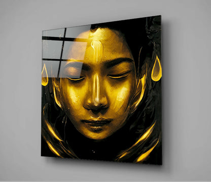 Golden sculptural face with closed eyes on black background, mounted behind clear glass panel with black grid overlay.