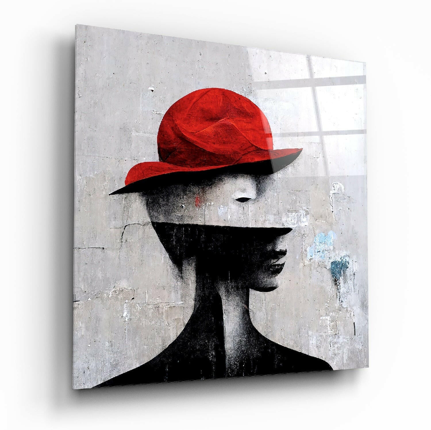 Glass wall art featuring a black silhouette profile wearing a striking red hat against a textured gray concrete background.