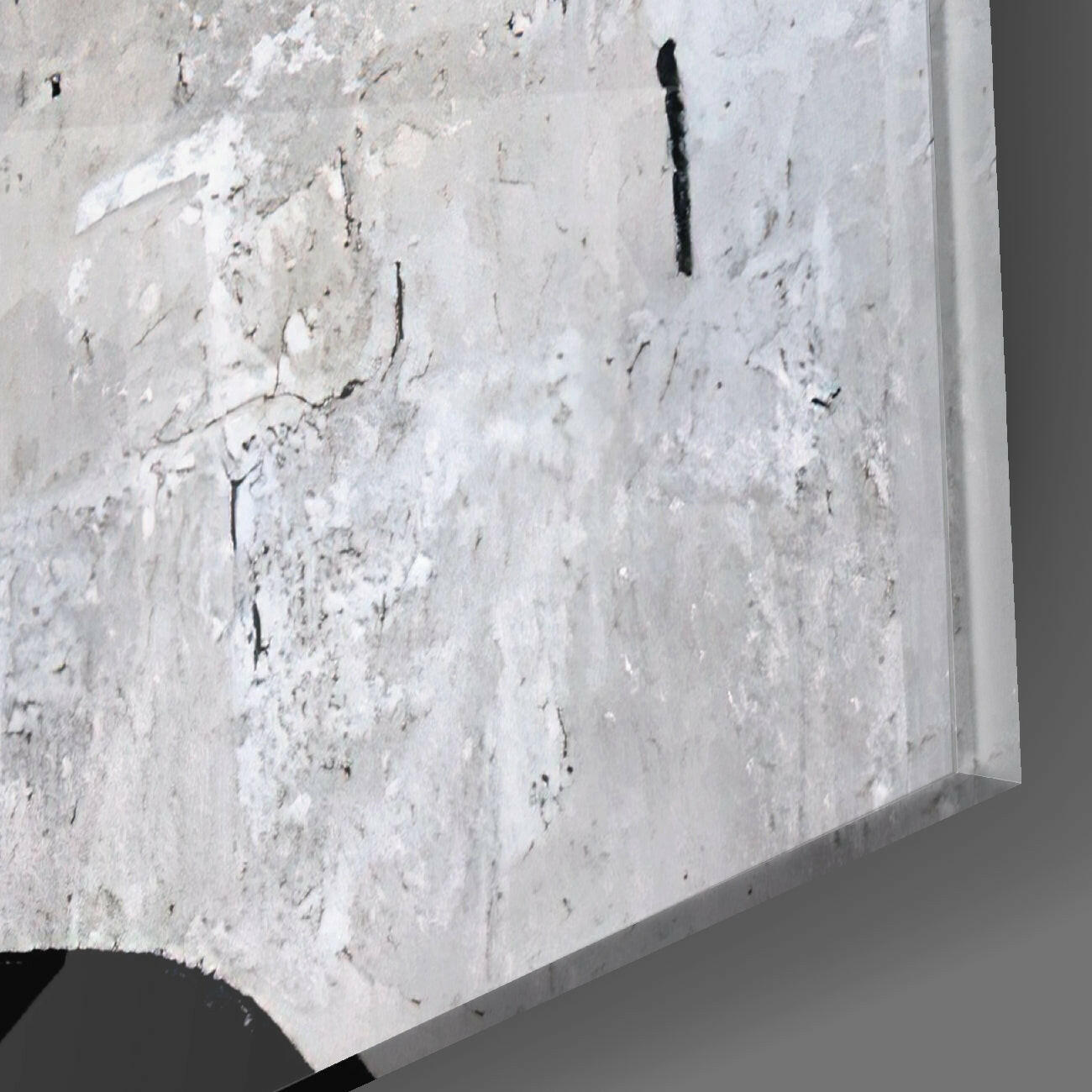 Close-up detail of textured white concrete surface with black cracks and shadow edge of glass panel visible.