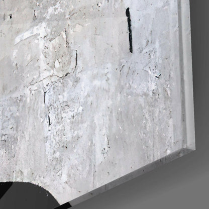 Close-up detail of textured white concrete surface with black cracks and shadow edge of glass panel visible.