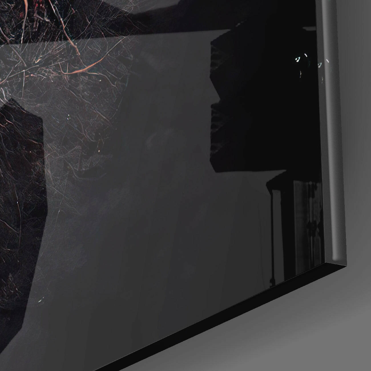 Close-up angled view of black glass wall art panel with white silhouette profile and bare branch design against dark background.