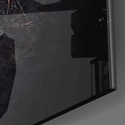 Close-up angled view of black glass wall art panel with white silhouette profile and bare branch design against dark background.