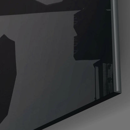 Close-up angled view of black glass wall art panel mounted on white wall, showing silhouetted tropical design against light background.