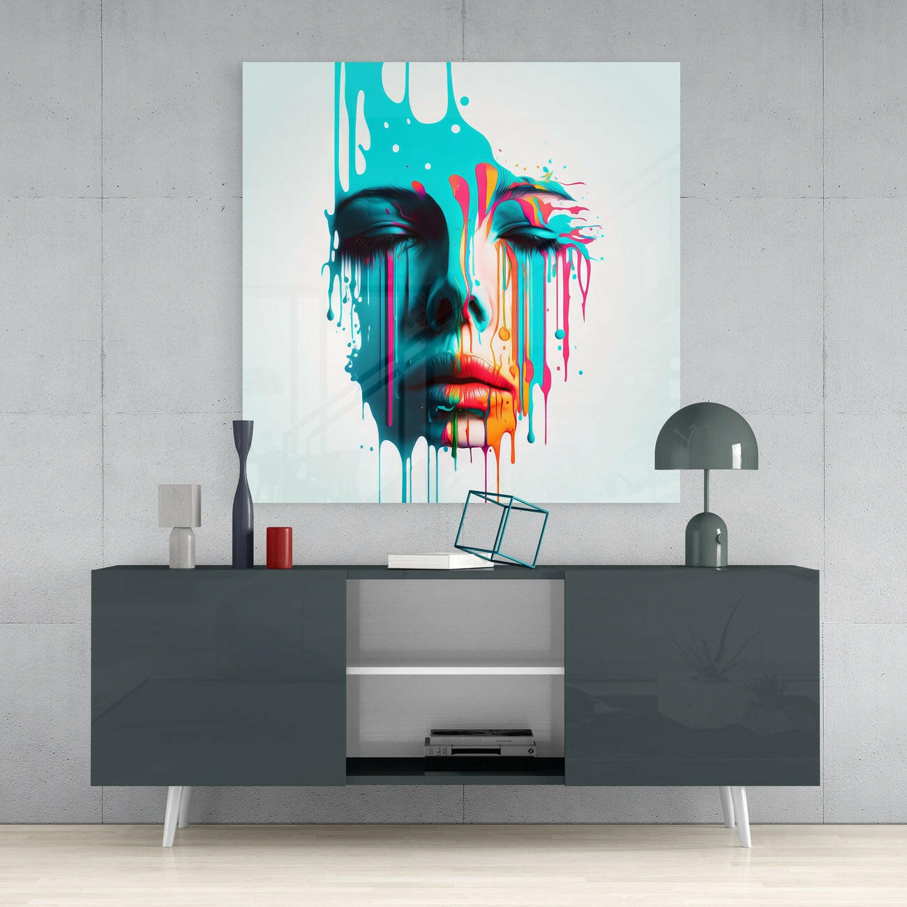 Colorful abstract portrait glass wall art displayed above dark console table with decorative accessories and lamp.