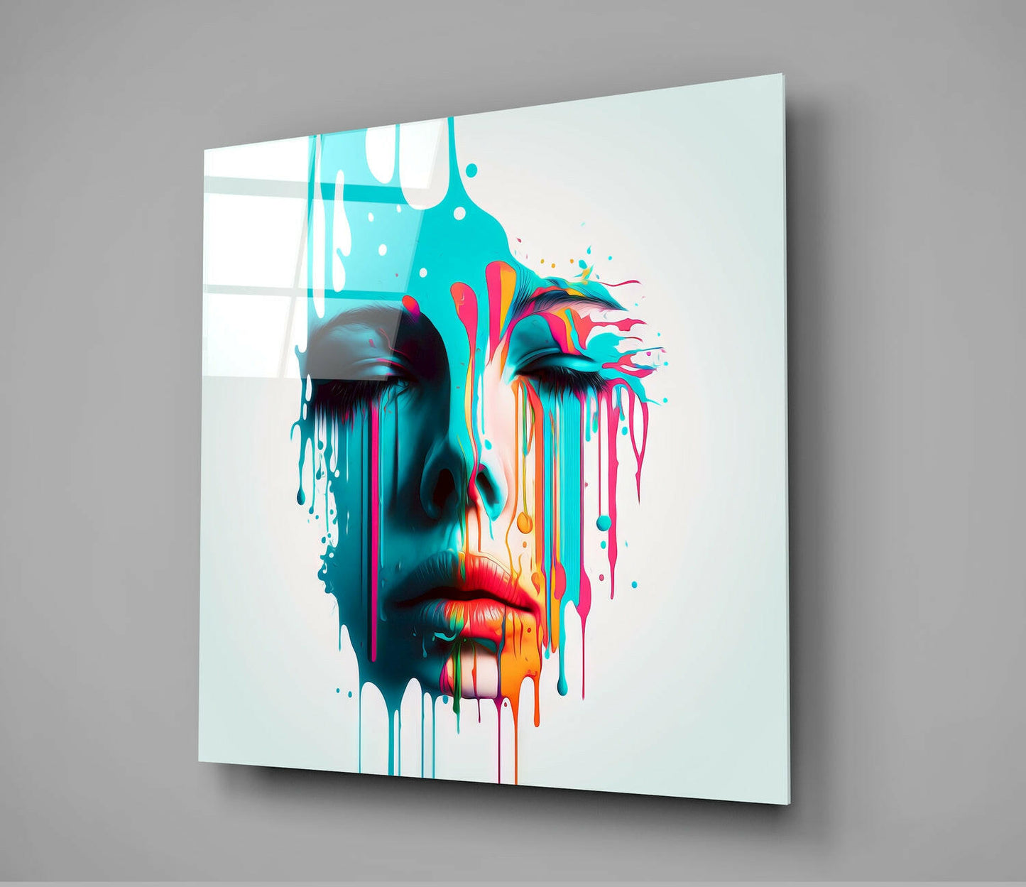 Angled view of glass wall art displaying a colorful abstract face with cyan, magenta, yellow, and red paint drips against white background.