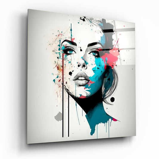 Modern glass wall art featuring an abstract female face in black line work with turquoise and pink watercolor splashes on white background, angled perspective view.