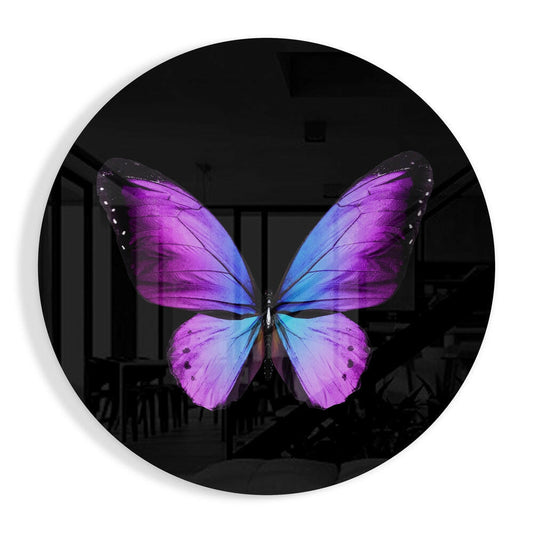 Vibrant purple and blue butterfly centered on round black glass wall art, displayed against dark interior background.