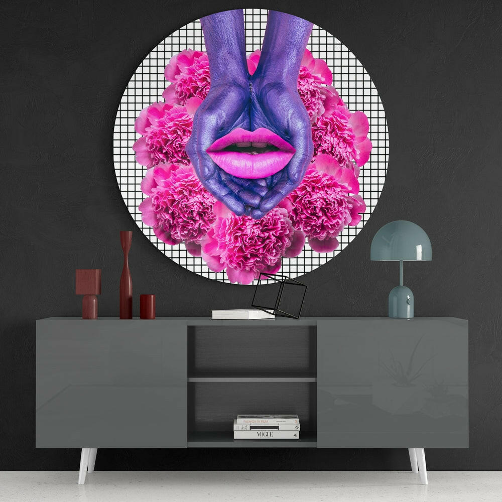 Purple hands and pink lips with magenta carnation flowers arranged in circular glass wall art displayed above gray console table.