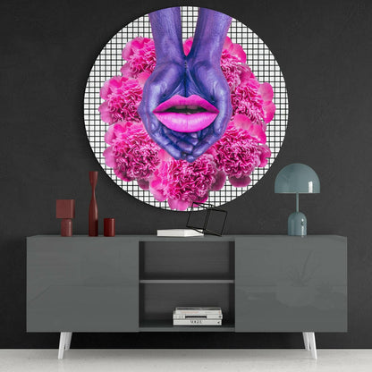 Purple hands and pink lips with magenta carnation flowers arranged in circular glass wall art displayed above gray console table.