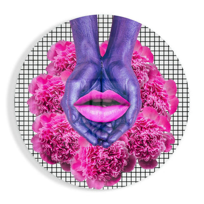 Purple painted hands forming heart shape with bright pink lips and magenta peonies on gridded background circular glass art.