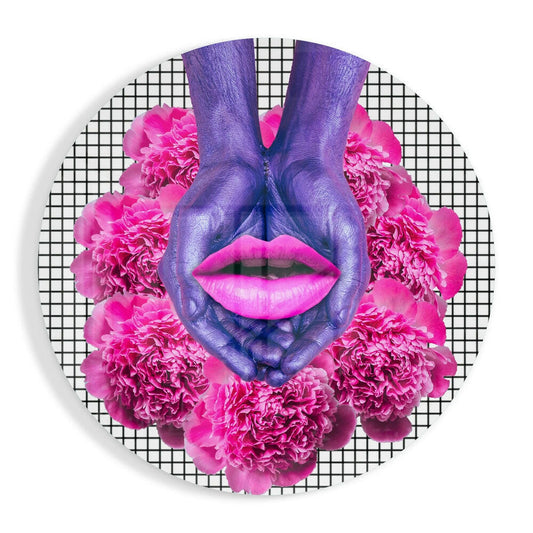 Purple painted hands forming heart shape with bright pink lips and magenta peonies on gridded background circular glass art.