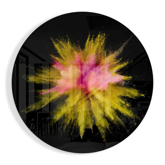 Circular black glass panel featuring a radial explosion of yellow and pink powder bursting outward from the center against a dark background.